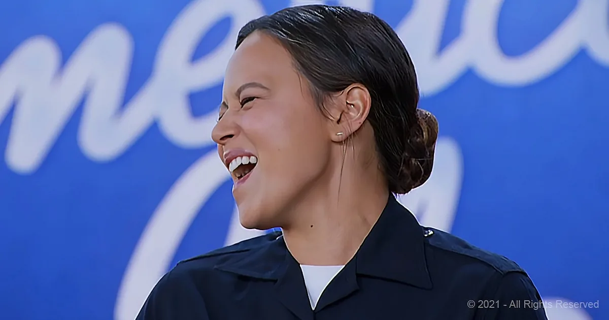 A smiling woman in a dark uniform with a bun hairstyle, standing in front of a blue background with white text.