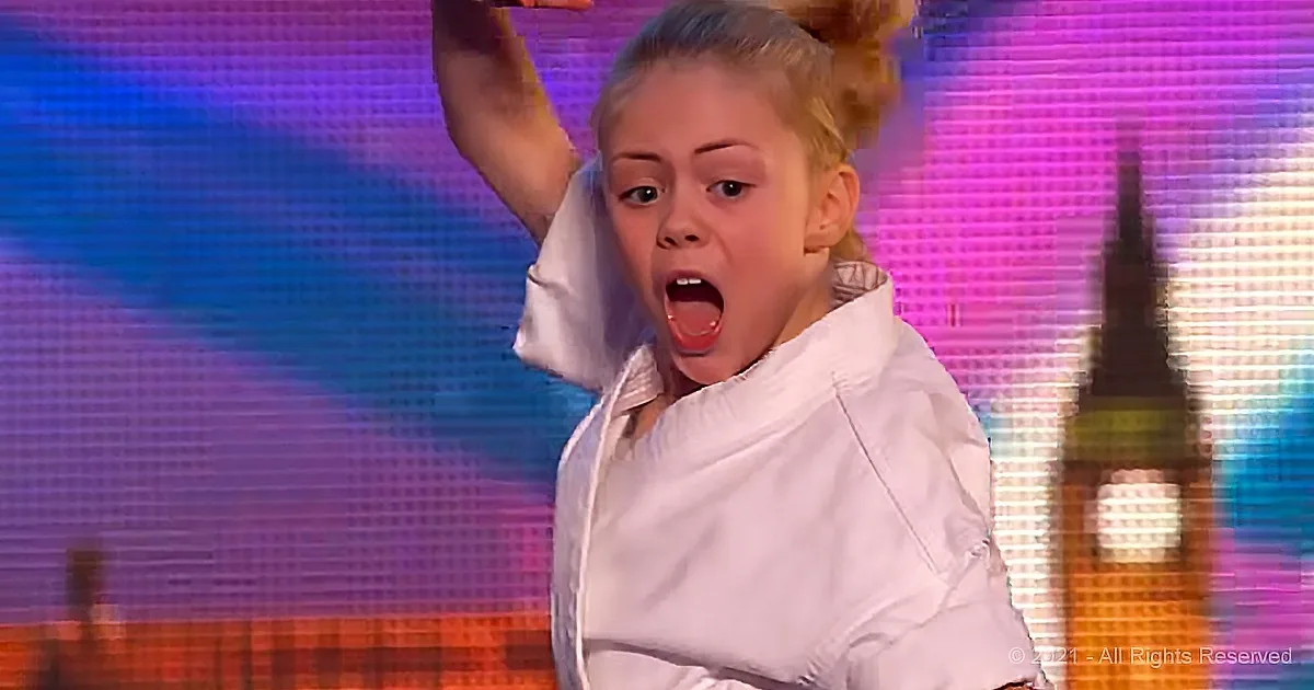 A young girl in a white shirt raises her arm, mouth open, against a colorful, illuminated background.