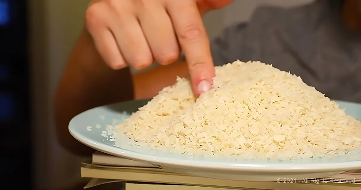 A hand points at a mound of shredded coconut on a light blue plate.