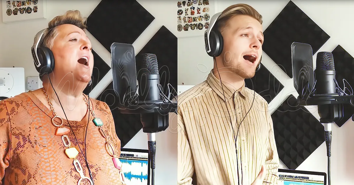 A woman and a man sing into microphones in a recording studio with acoustic foam panels.