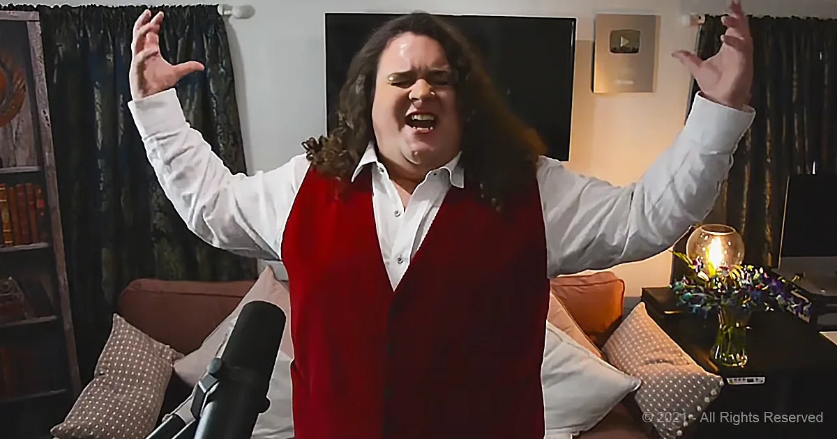 A person in a red vest and white shirt sings passionately with arms raised in a cozy room.