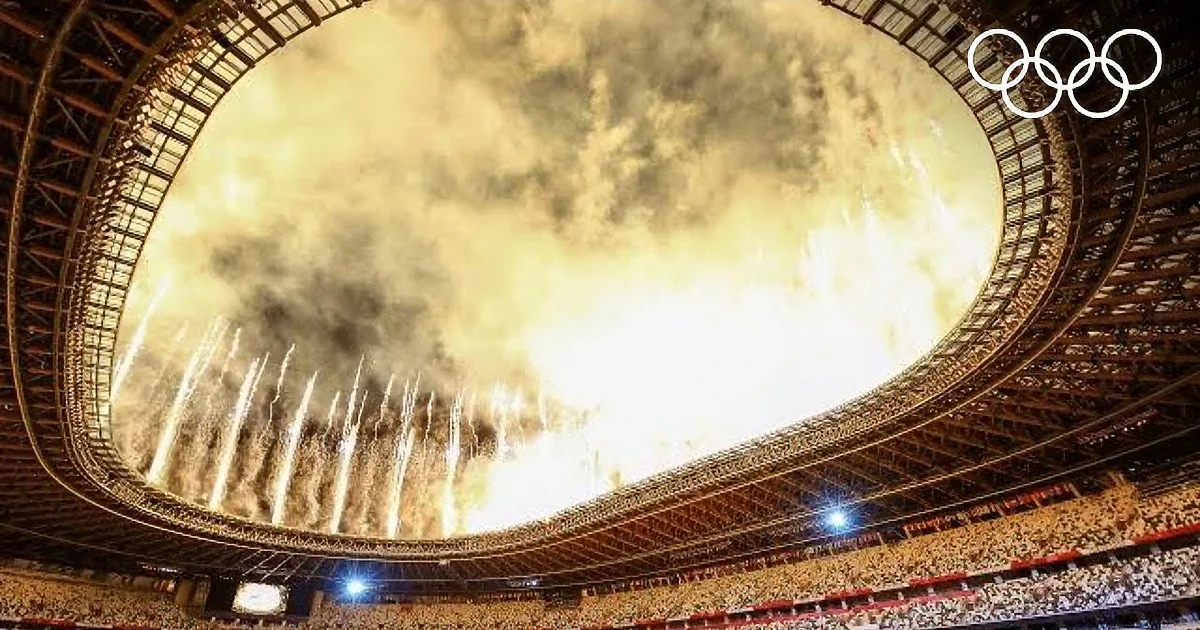 Fireworks lighting up the sky above a stadium with "Tokyo 2020" displayed on its facade.