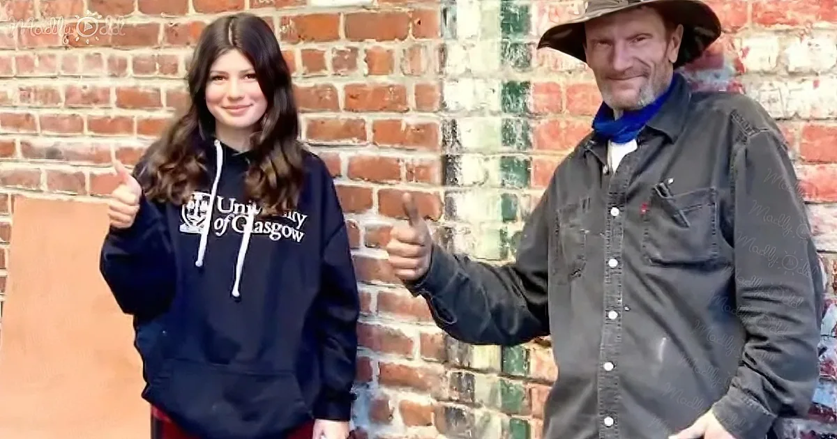 A man and a girl give thumbs up, both smiling, against a brick wall backdrop.