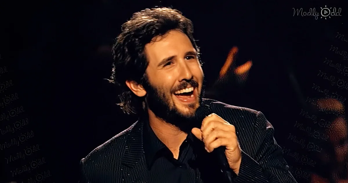 A man with curly hair and a beard sings into a microphone, wearing a dark suit.