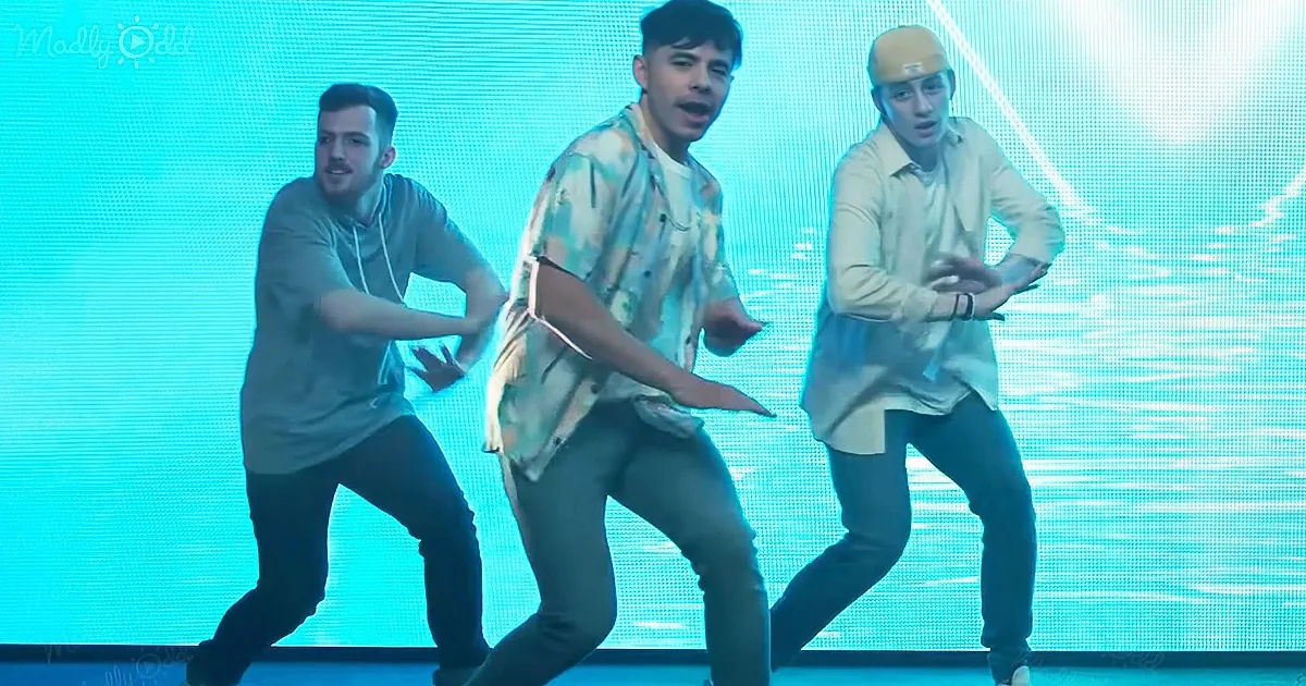 Three men dance energetically on stage with a blue LED background.