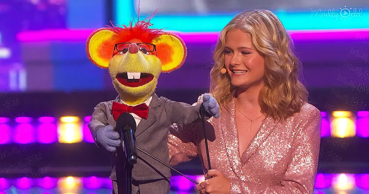 A person in a pink sequined dress stands beside a puppet in a suit, both holding microphones on a stage with colorful lights.