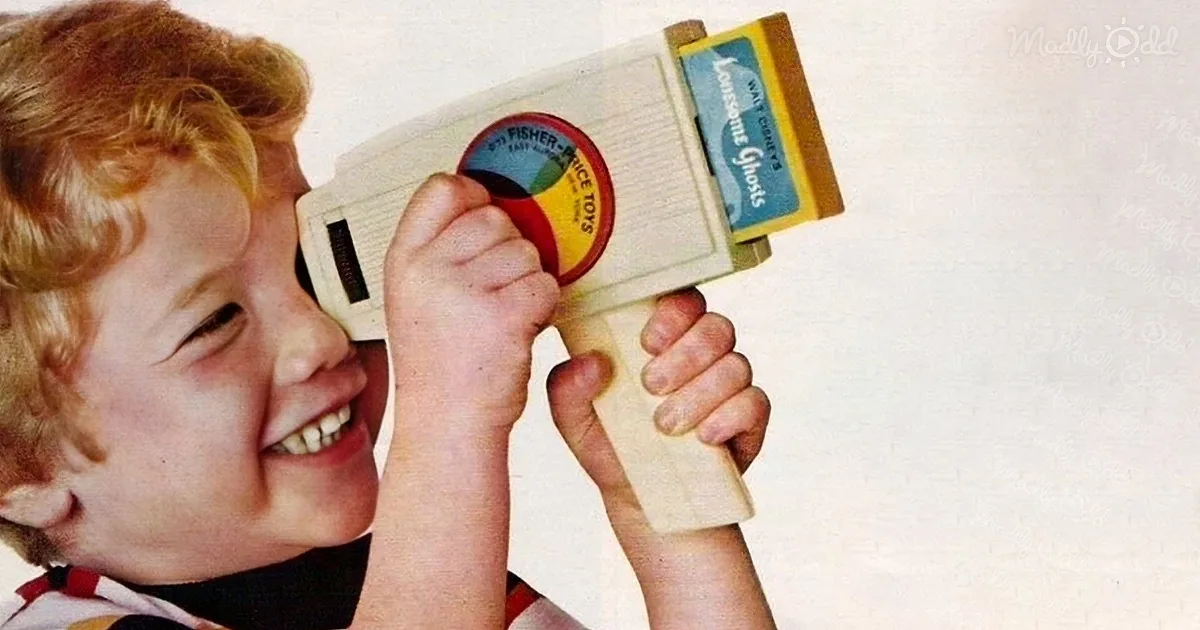 A child smiles while holding a Fisher-Price toy camera labeled "Lonesome Ghosts."