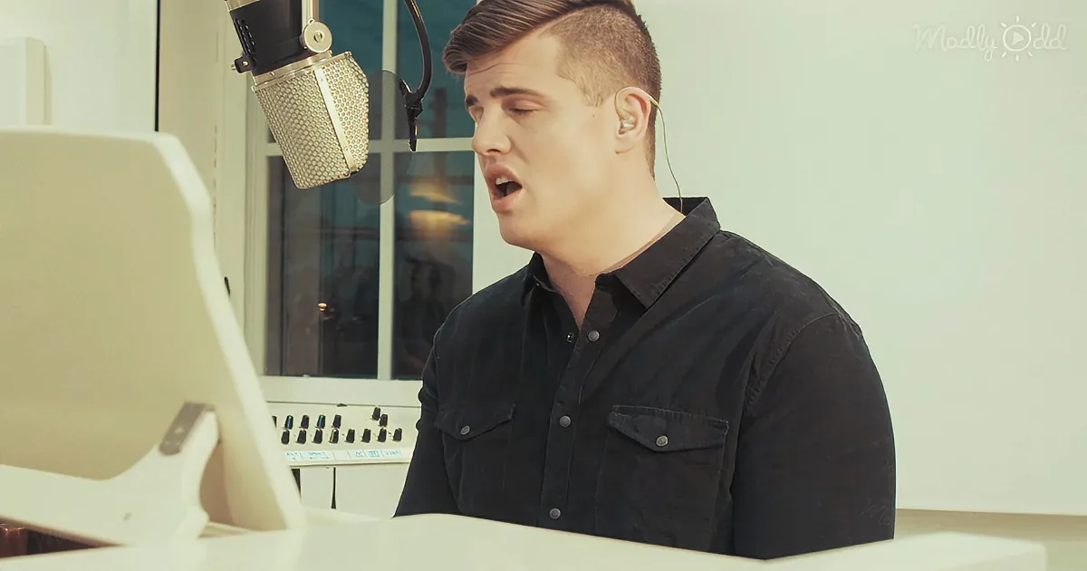 A man in a black shirt sings into a microphone in a recording studio.