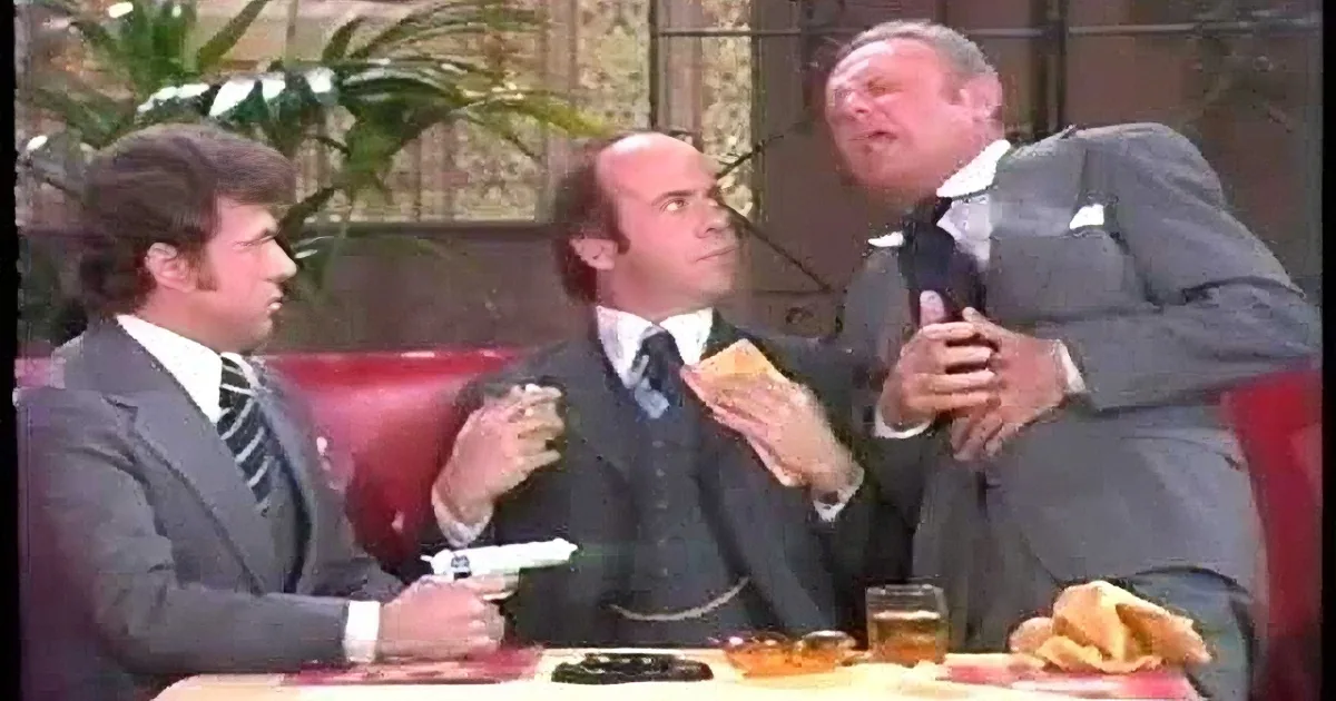 Three men in suits sit at a table, laughing and enjoying a moment together.