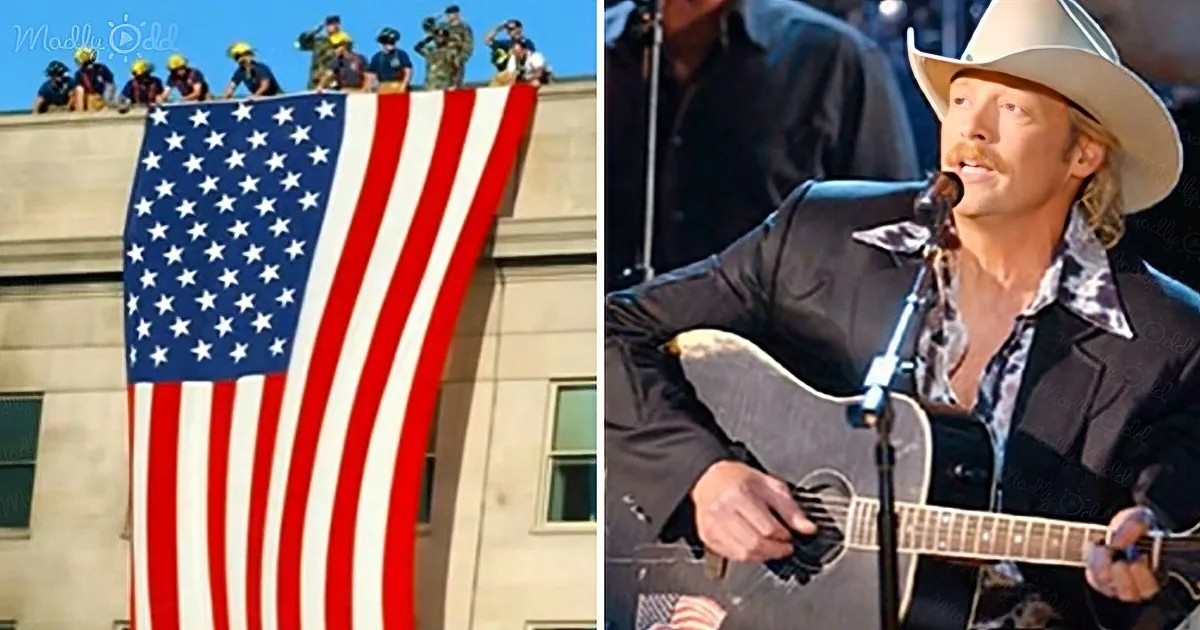 A man in a cowboy hat plays guitar while a large American flag is displayed by a group of people.