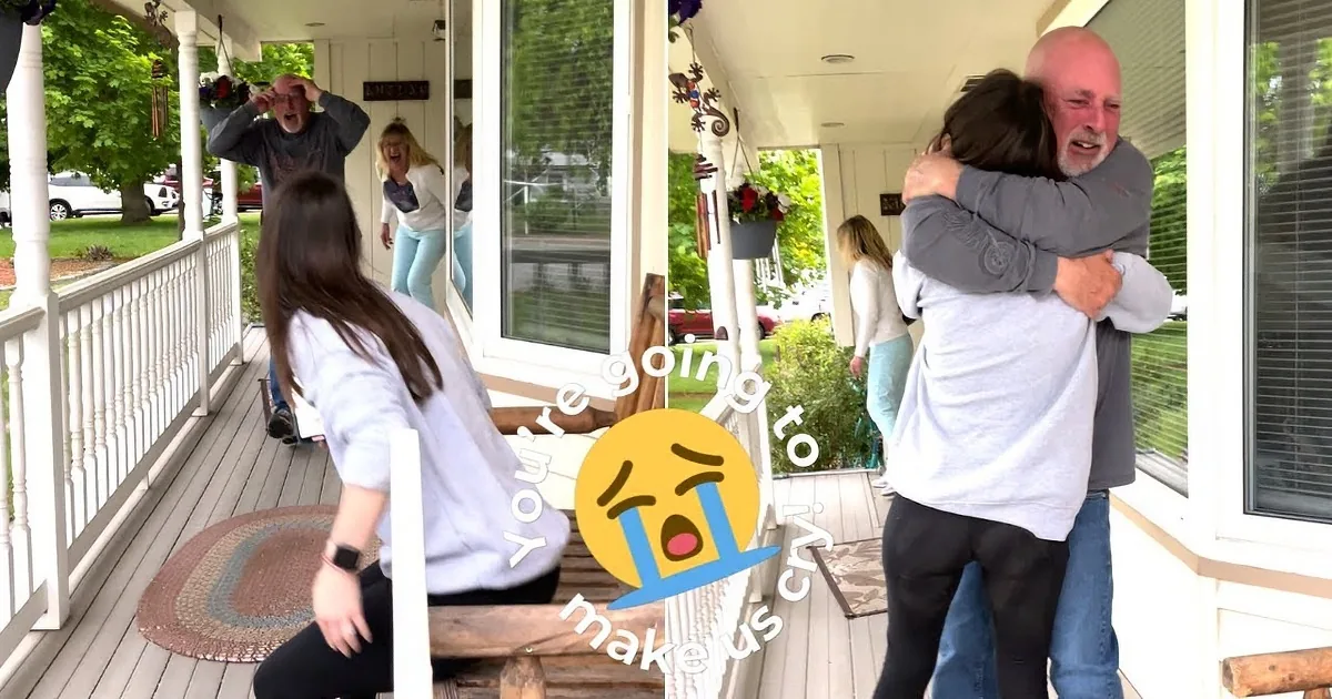 A man in a gray shirt hugs another person on a porch, with greenery and a car in the background.