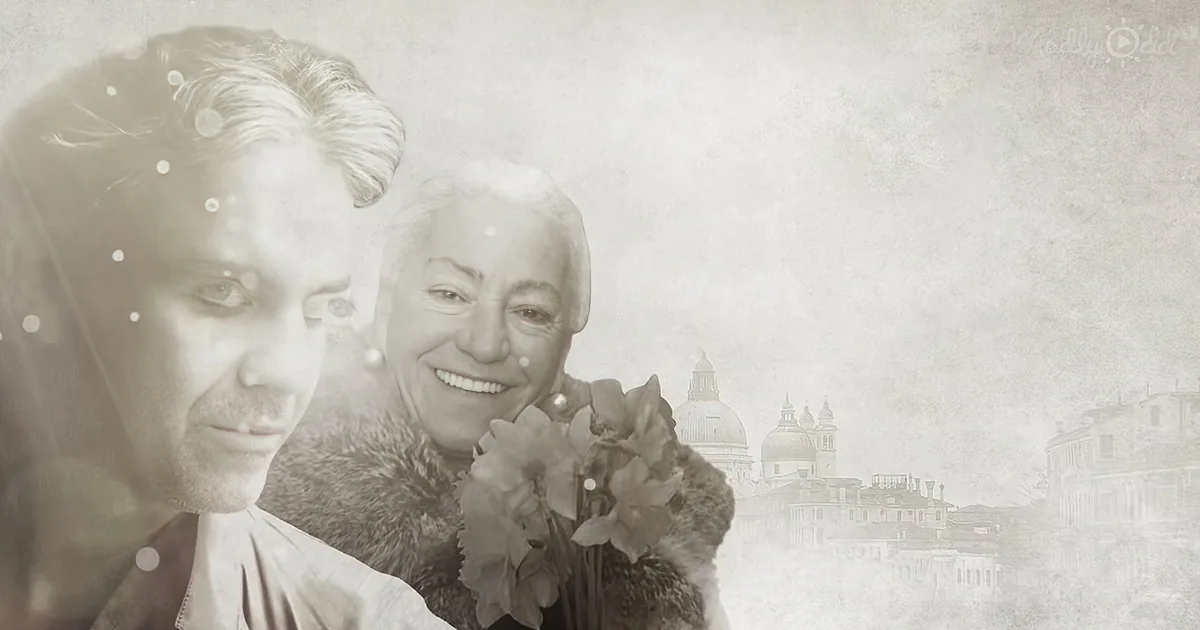 A smiling woman holding flowers, with a man beside her, both in a sepia-toned image with a cityscape in the background.