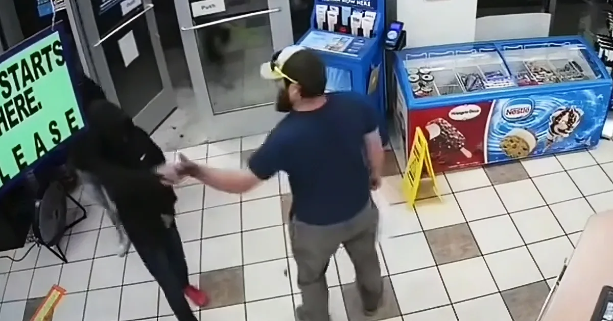 A man in a blue shirt and cap is reaching out to a person in a black hoodie near a frozen dessert display.