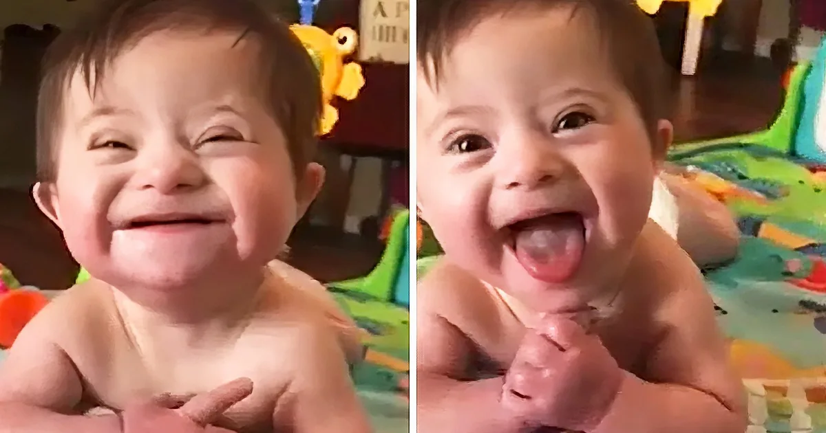 A joyful baby smiles widely, showing teeth and tongue, in a colorful play area.