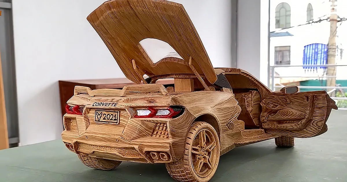 A detailed wooden model of a Corvette with an open hood and "2021" license plate.