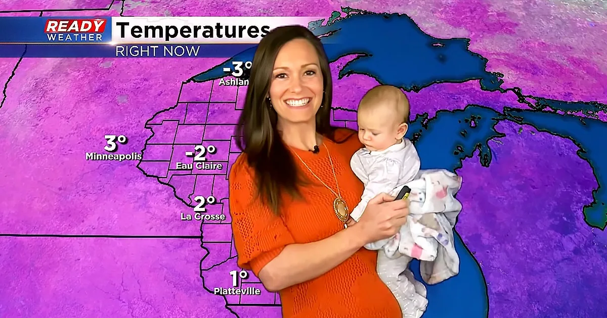A woman in an orange dress holds a baby while standing in front of a purple weather map showing temperatures.