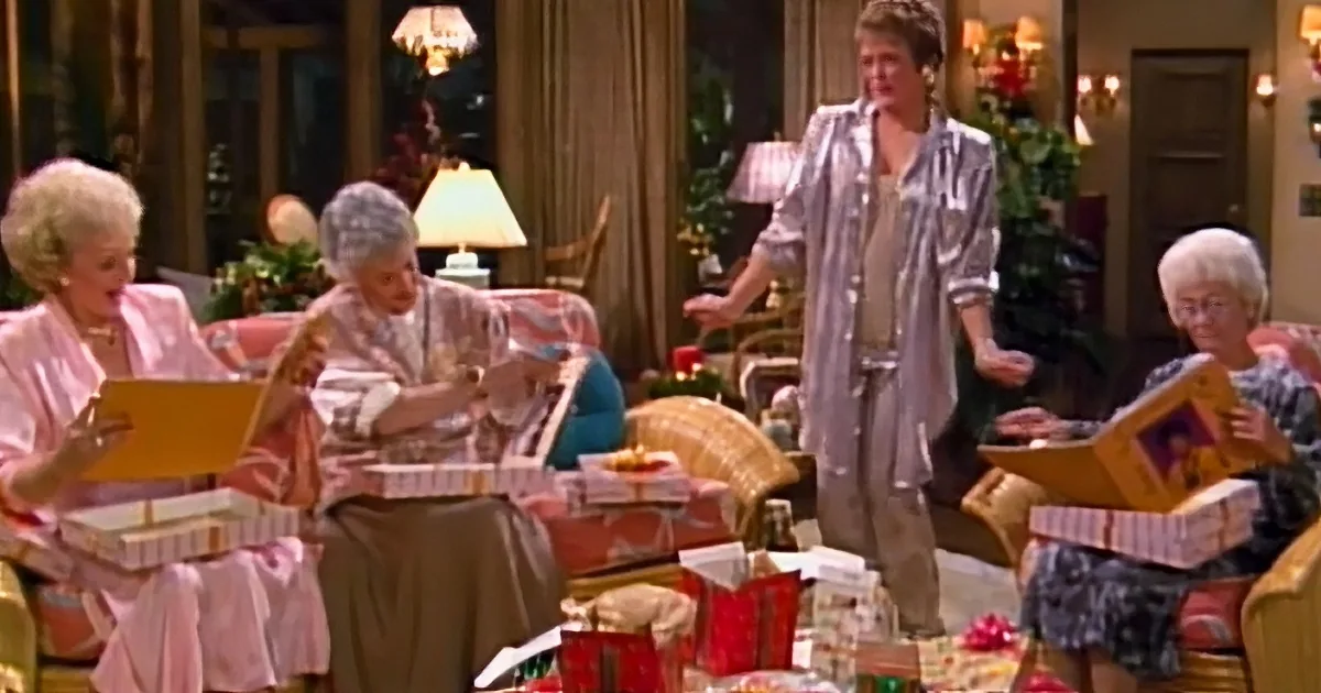 A woman in a robe stands amidst a group of women in robes, surrounded by wrapped presents in a cozy living room.