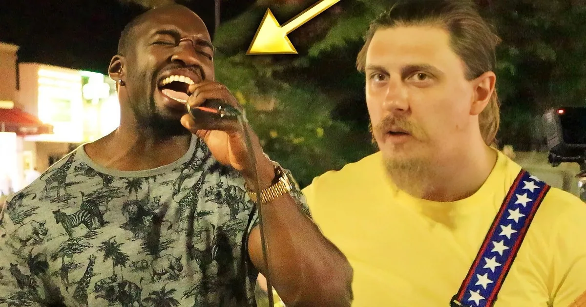 Two men sing into microphones, one wearing headphones, in a festive outdoor setting with lights.