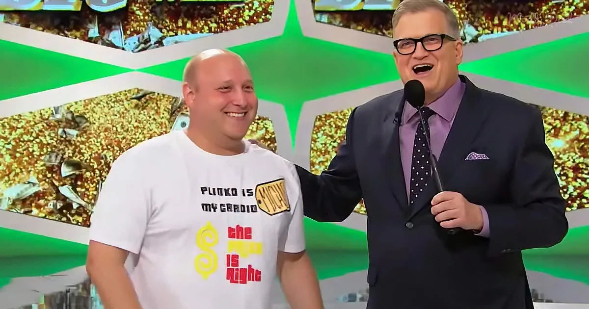 A man in a white t-shirt with "Plinko is my cardio" stands next to a man in a suit holding a microphone.
