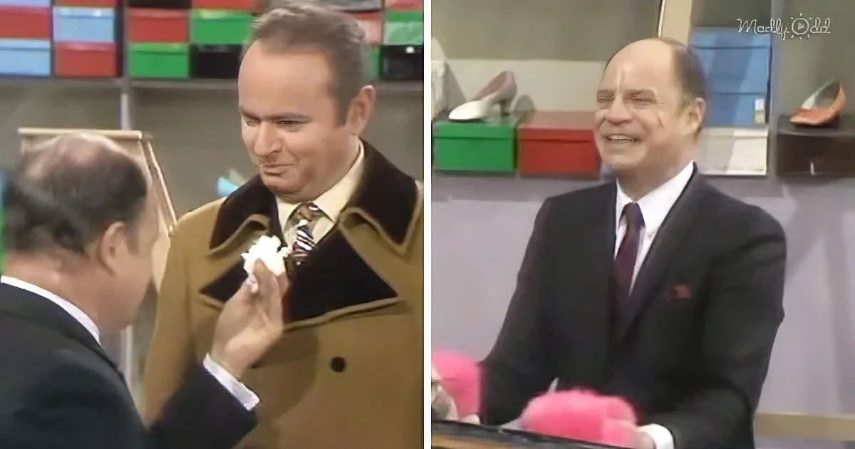 A man in a brown coat is being assisted by another man in a suit, possibly in a retail setting.