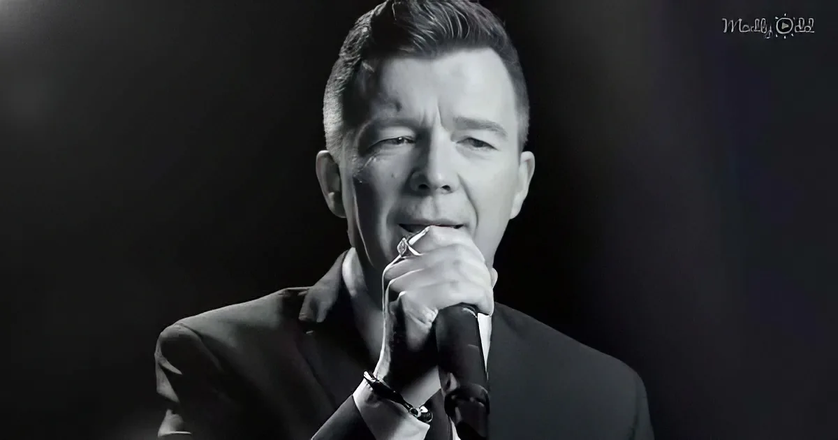 A man in a suit sings into a microphone against a dark background.