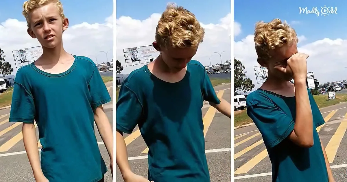 A young boy with blonde hair in a teal shirt stands in a parking lot, looking down and covering his face in different poses.