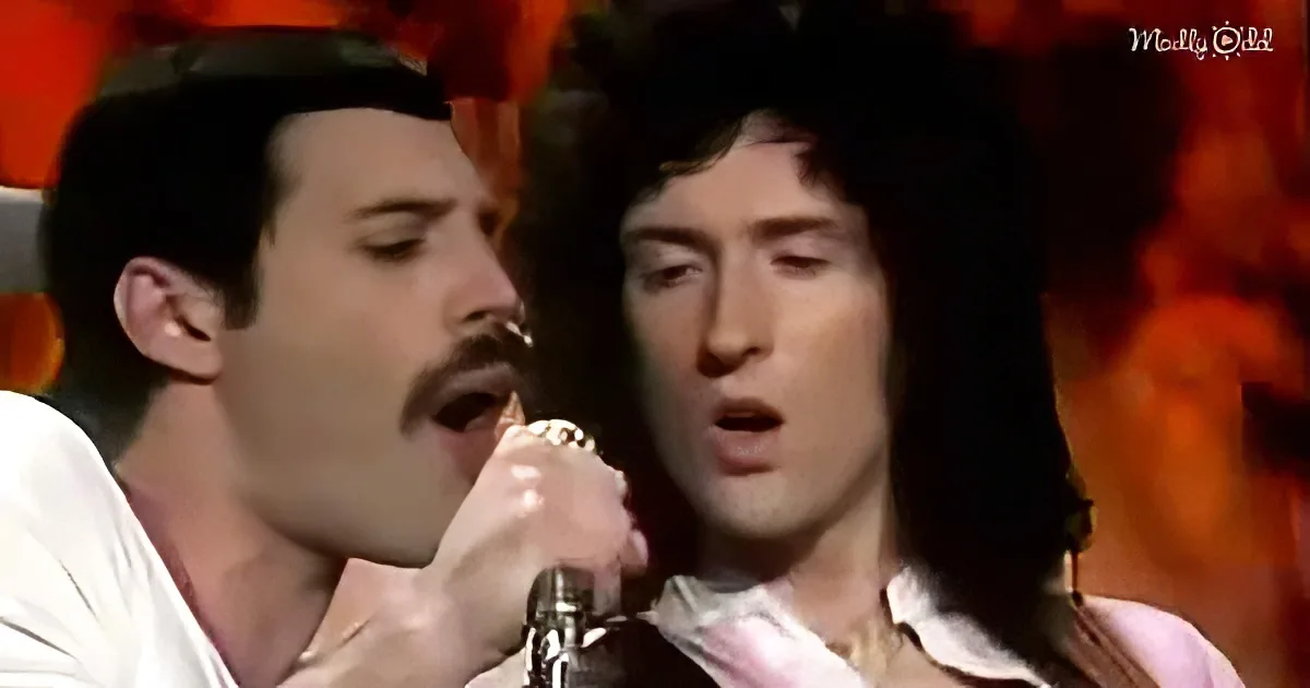 Two individuals singing passionately, one holding a microphone, both wearing white shirts, against a vibrant orange...