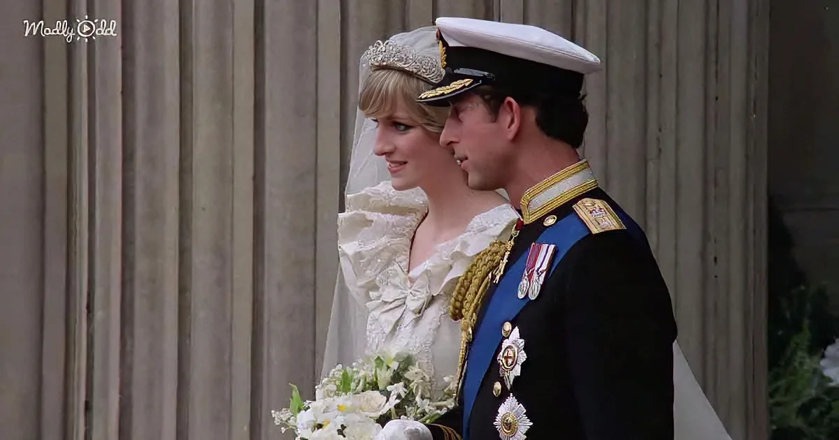 A bride in a white gown and tiara stands beside a man in a military uniform, both holding a bouquet of white flowers.