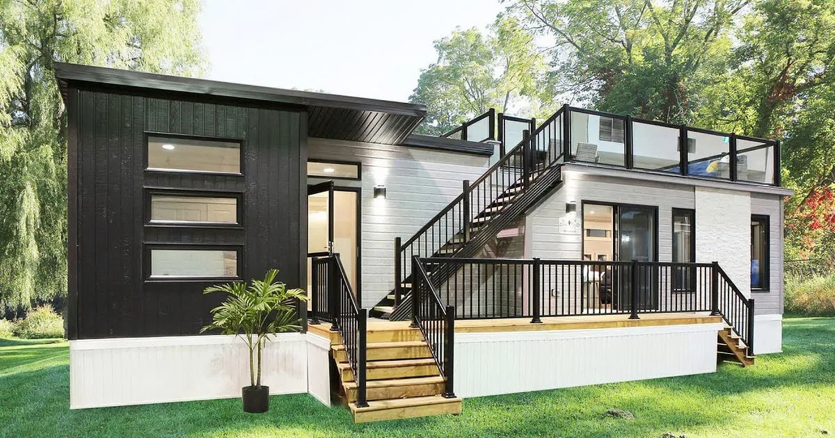 A modern house with large windows, stone accents, and a covered patio surrounded by lush greenery.
