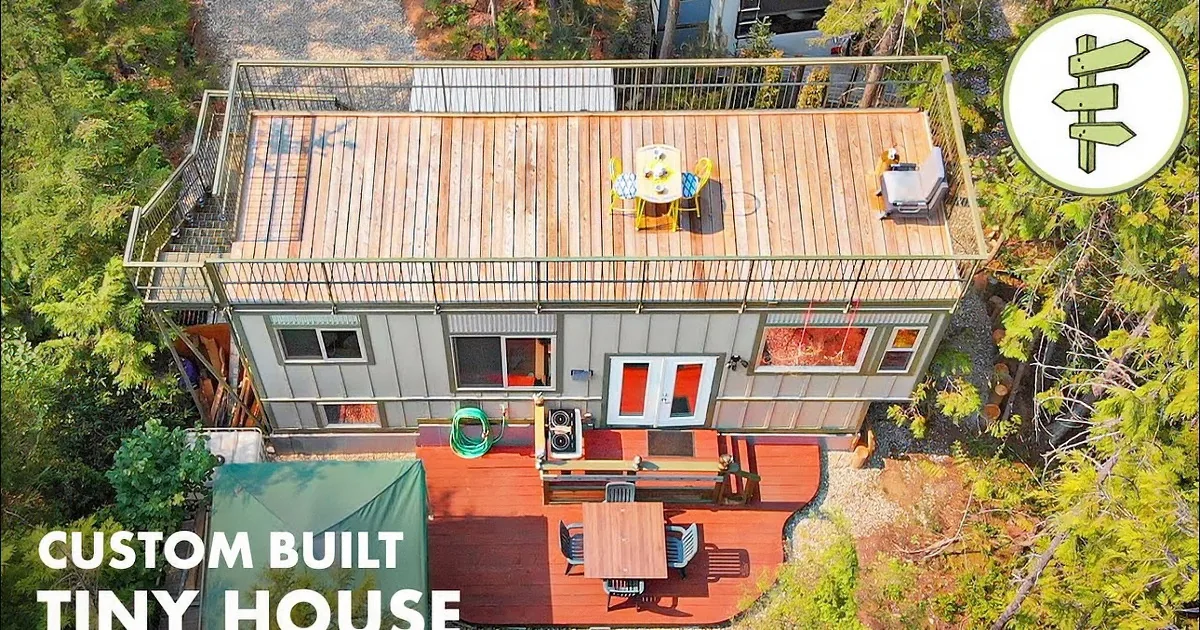 A modern house with a large deck surrounded by trees and a small outdoor kitchen area.