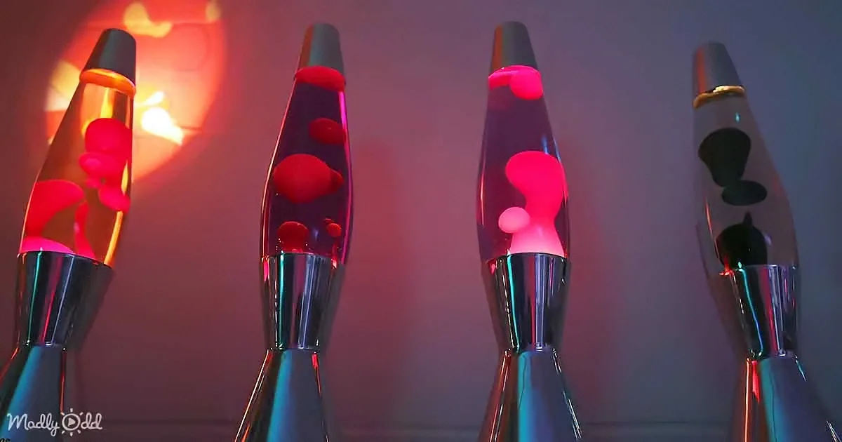 Four lava lamps with red and pink wax floating in clear liquid, glowing softly against a dark background.