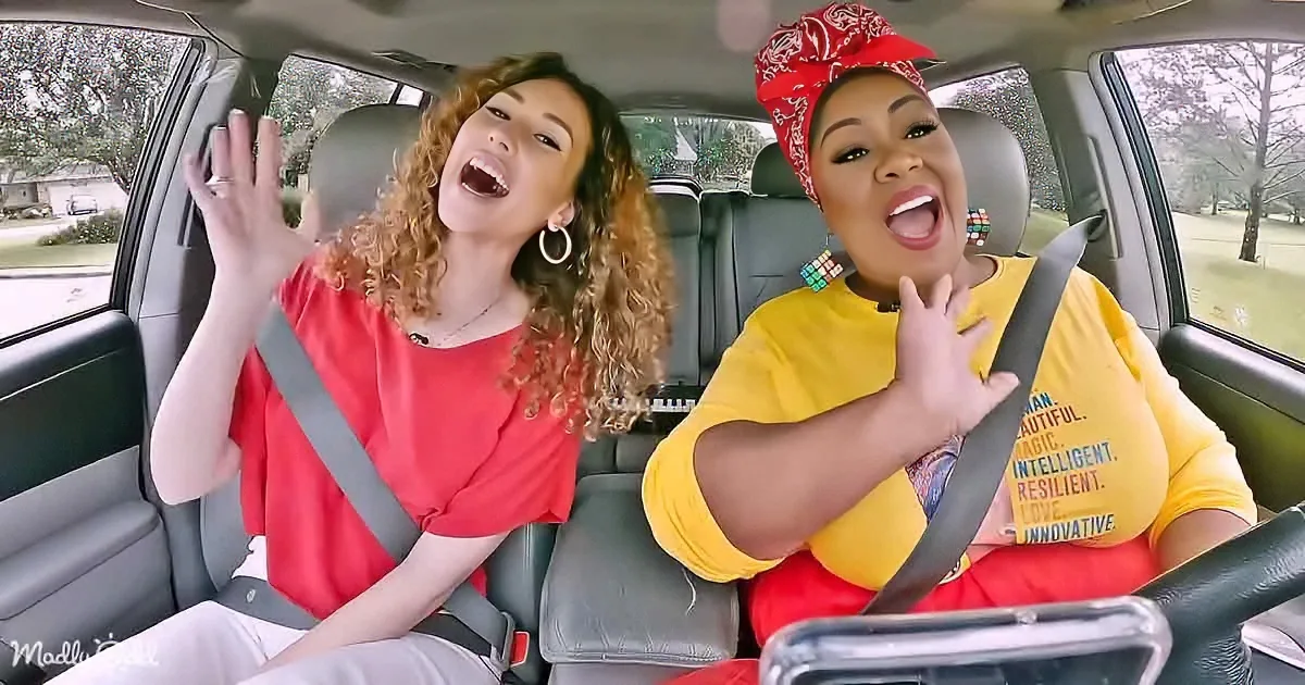Two women in a car, one in red, the other in yellow, both making expressive gestures and faces.