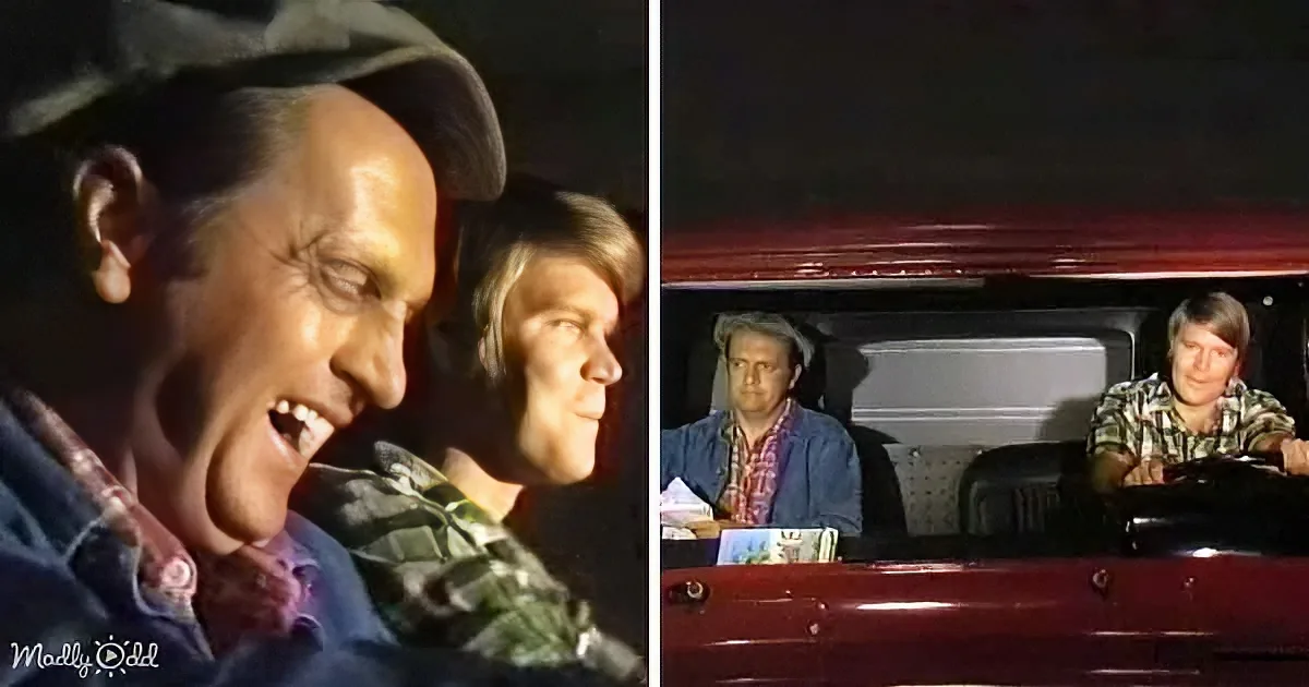 A man in a truck laughs heartily, with another person in the passenger seat, both appearing amused.