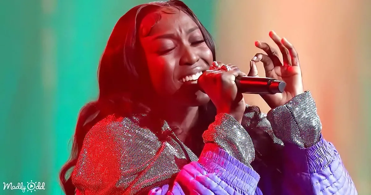 A person in a red and purple outfit is singing passionately into a microphone.