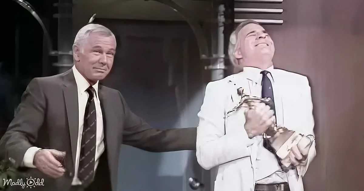 A man in a suit is laughing heartily while another man in a suit looks on with a concerned expression.