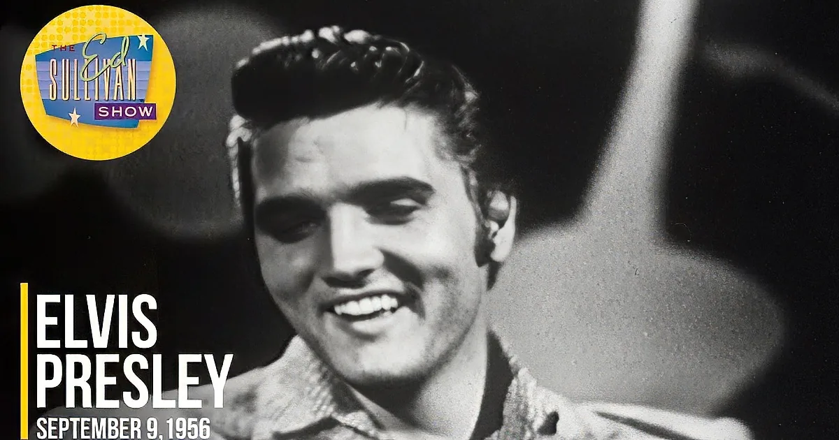 A close-up of Elvis Presley in a black-and-white scene, wearing a textured shirt, with a blurred figure in the background.