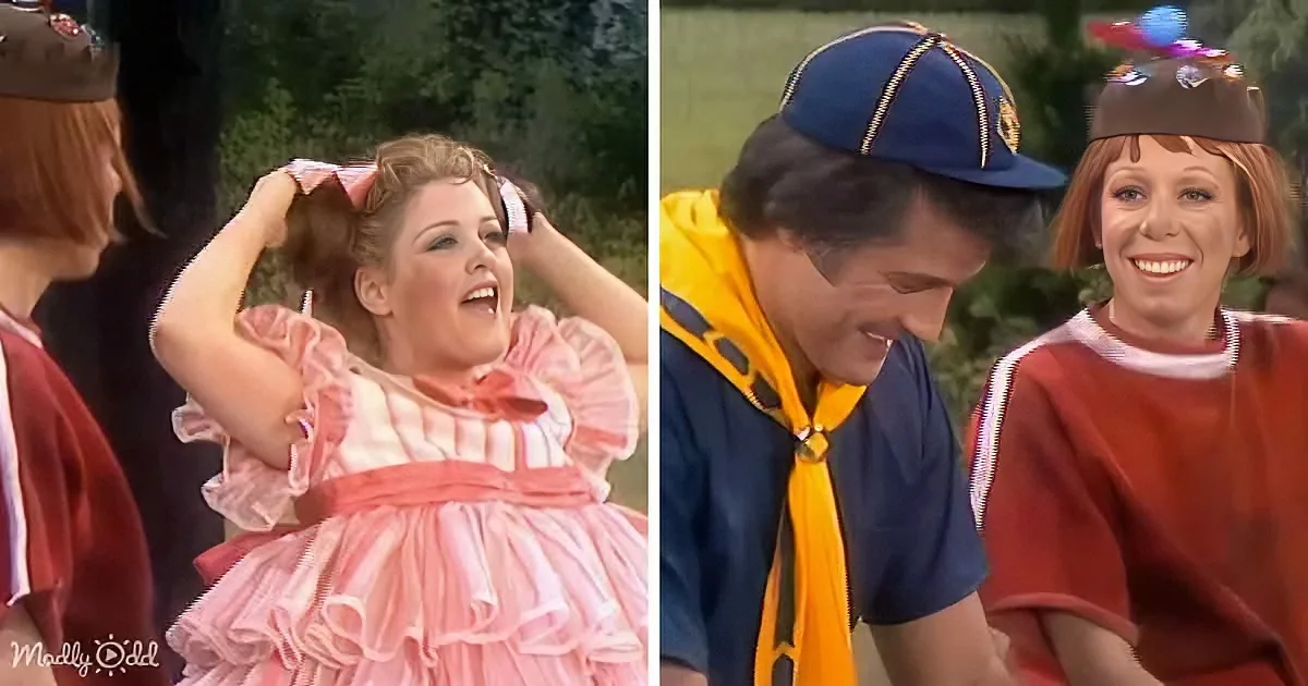 A woman in a pink ruffled dress is adjusting her hair, while a man in a blue cap and yellow scarf looks down, with...