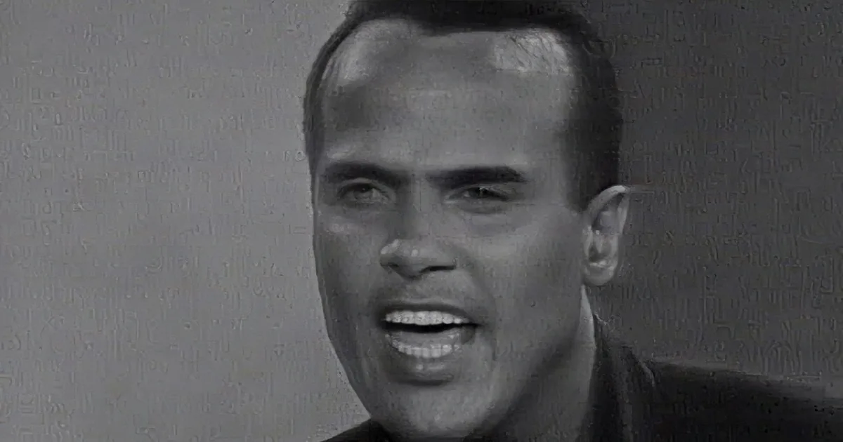 A man with a receding hairline and a slight smile, wearing a dark suit, is the main subject of this black-and-white image.