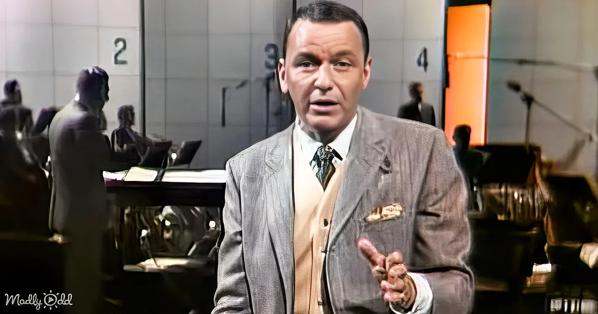 A man in a gray suit gestures with his right hand in a courtroom setting.
