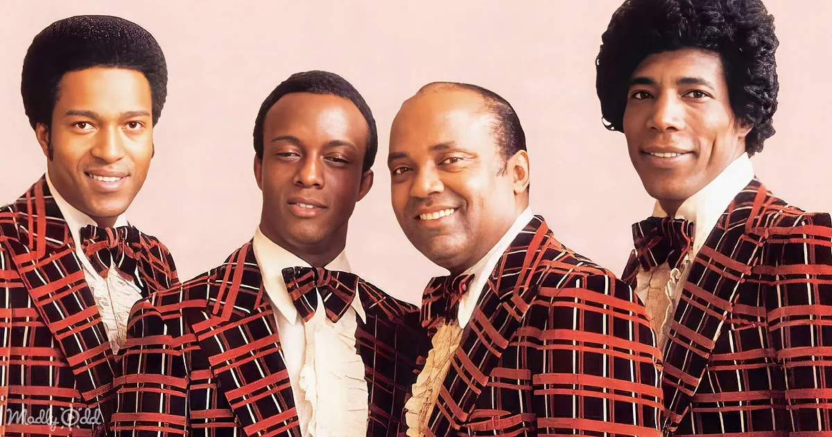 Four men in matching red plaid suits and bow ties pose together, smiling.