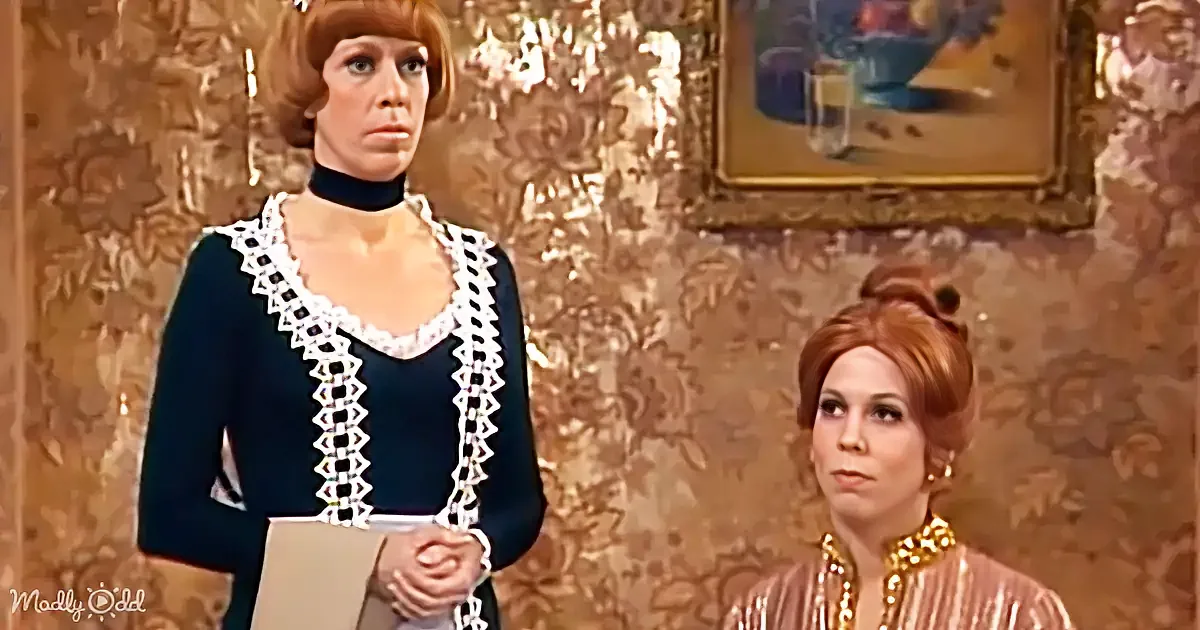 A woman in a dark blue dress with white trim stands, holding a folder, while another woman in a pink dress with gold...