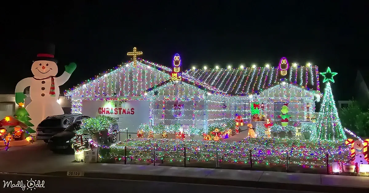 A house adorned with festive Christmas lights and decorations, including a giant snowman and holiday-themed ornaments.
