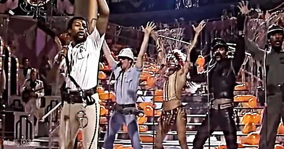 A man in a white shirt and hat raises his arms in celebration, surrounded by others in various attire.