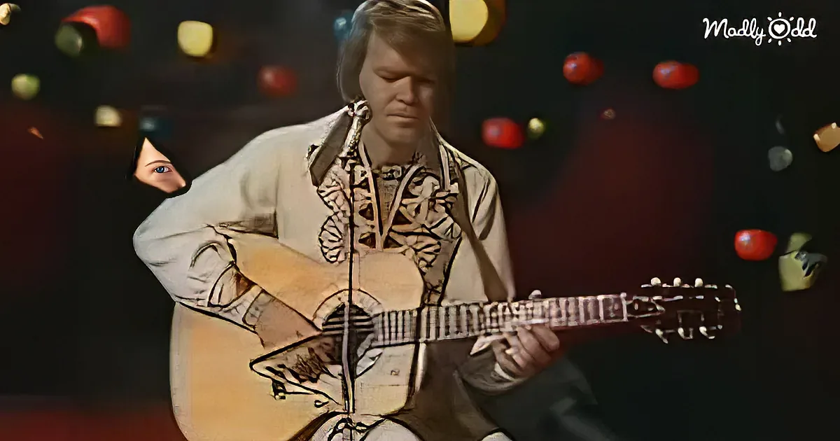 A person in a white shirt plays a guitar with a microphone in front, surrounded by floating colorful objects.