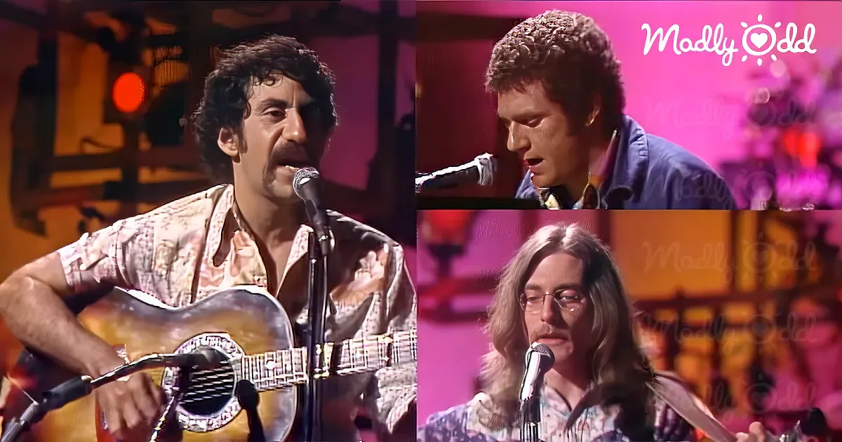 A man with curly hair plays guitar and sings into a microphone.