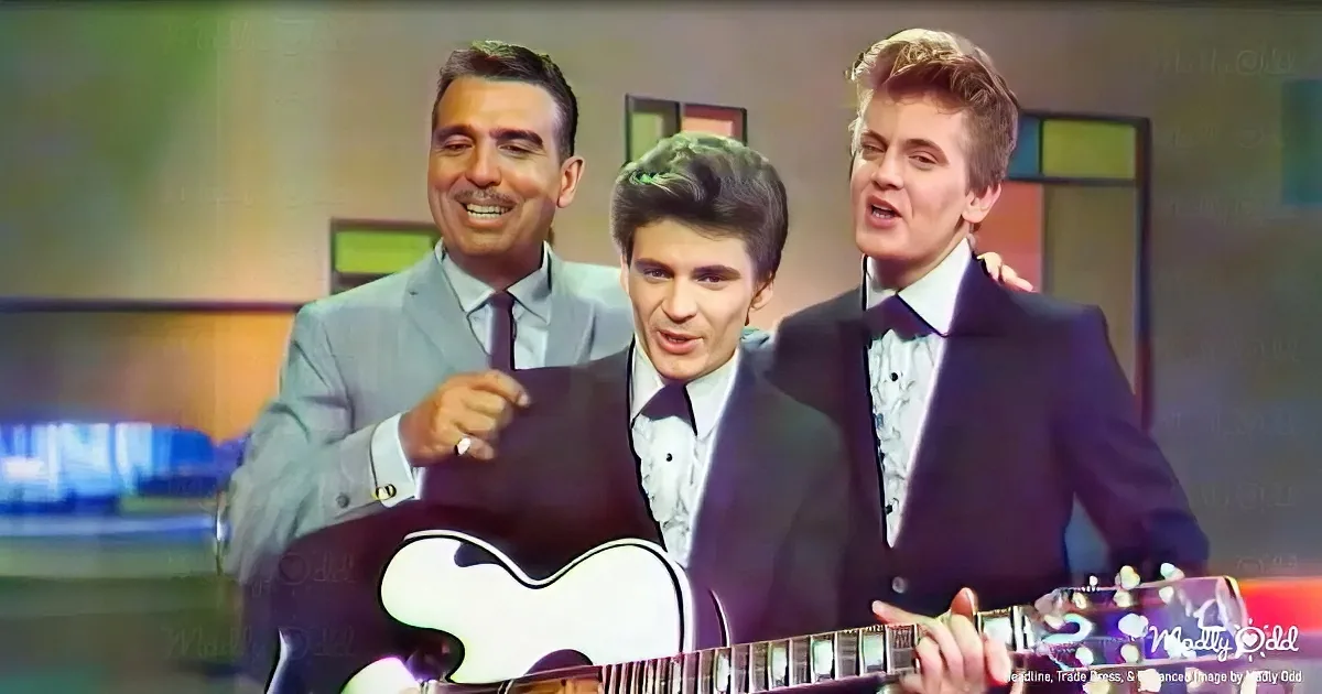 Three men in suits, one playing guitar, smiling, colorful background.