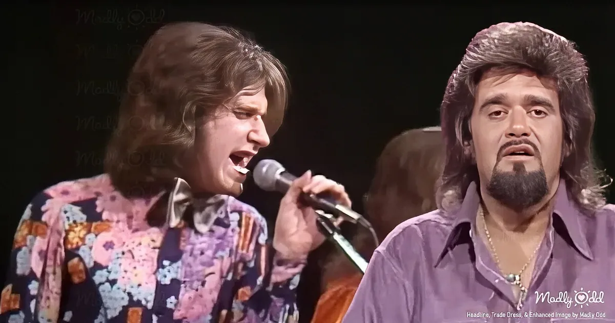 A man in a floral shirt sings into a microphone while another man in a purple shirt looks on.