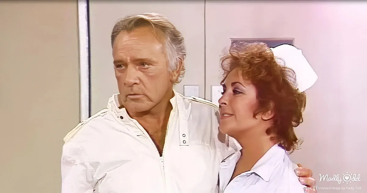 A man in a white jacket looks concerned as a woman with curly hair smiles beside him.