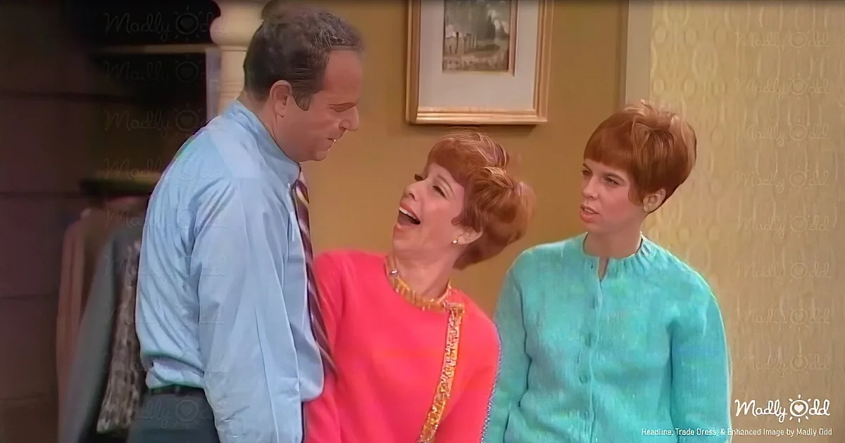A man in a blue shirt and tie is looking at a woman in a pink top and necklace, who is laughing.