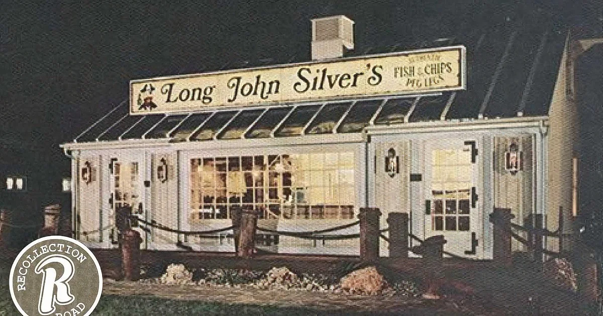 A Long John Silver's restaurant with a sign and a glass awning at night.